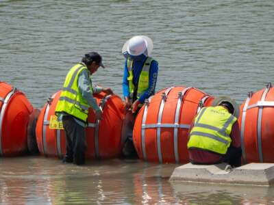 Workers provide maintenance to the blades between the buoys placed along the Rio Grande border with Mexico to prevent migrants from entering the U.S. in Eagle Pass, Texas, on August 25, 2023.