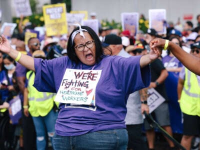 Demonstrator wearing a sign that says "We're fighting for health care workers"