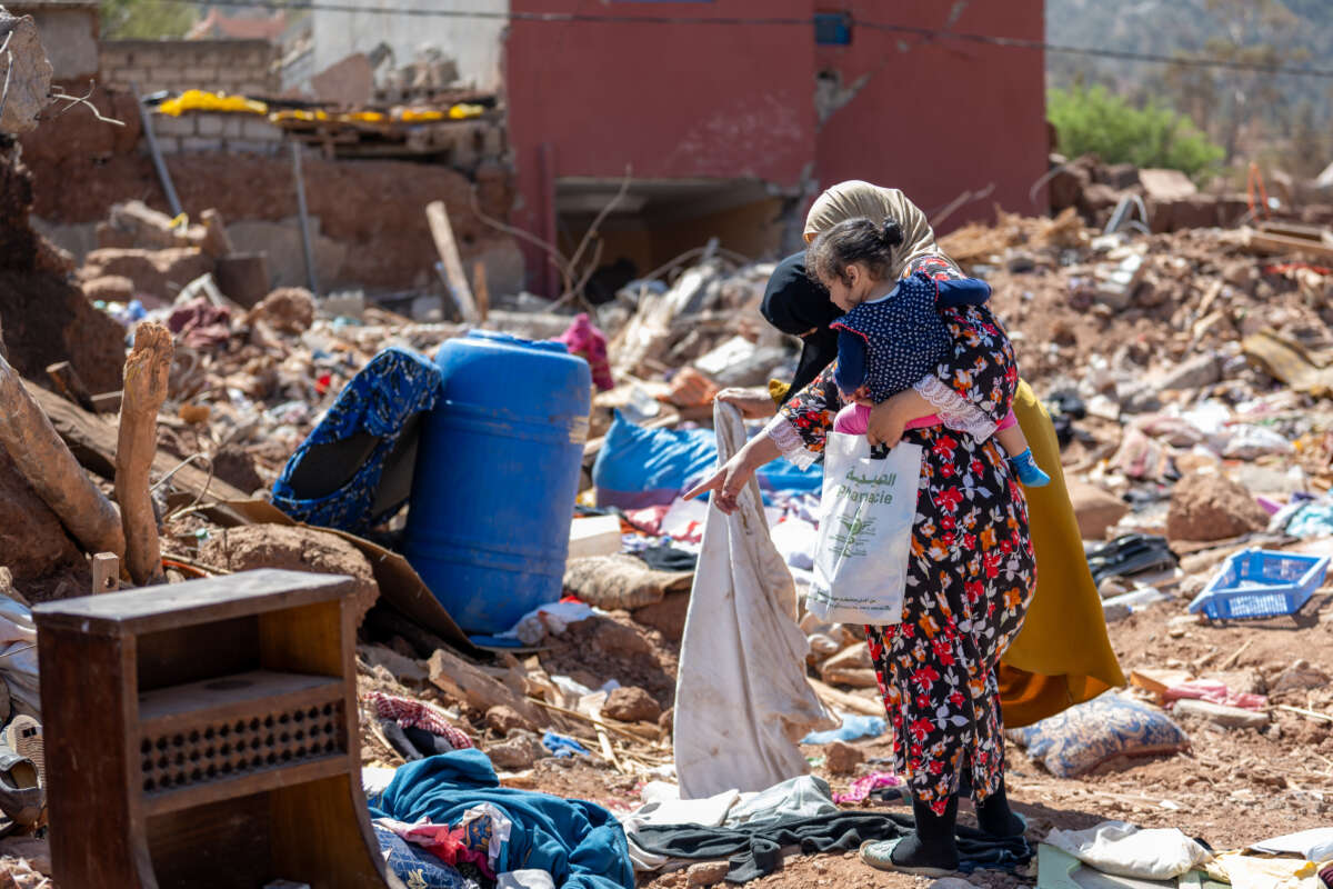 Two women and a child look for items in the rubble of their home in the village of Imzalin in Morocco