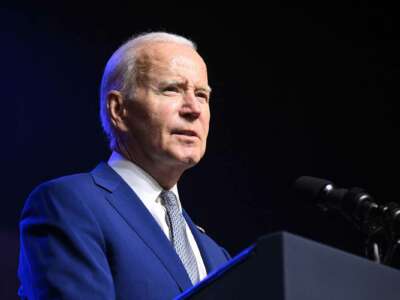 Joe Biden squints into the middle distance while standing at a podium