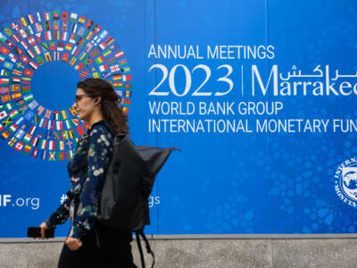 A pedestrian walks past a billboard announcing the World Bank Group and International Monetary Fund annual meetings, on the side of the International Monetary Fund headquarters in Washington D.C. on October 5, 2023.