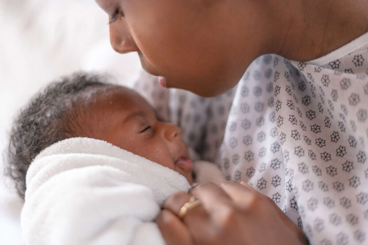 Black mother wearing hospital gown holds baby