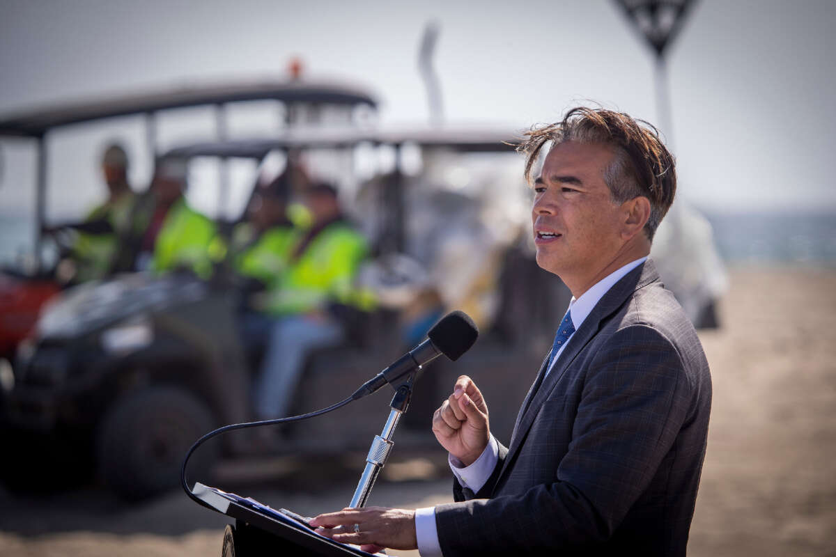 Oil spill cleanup workers listen as Attorney General Rob Bonta speaks about the oil spill response at Huntington State Beach in Huntington Beach, California, on October 11, 2021.