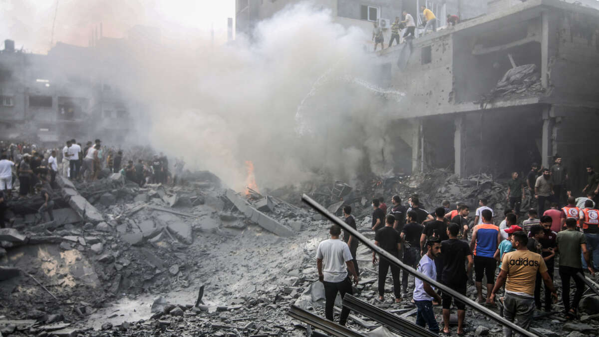 People extinguish a fire in the site of Israeli air strikes in Rafah on October 12, 2023.