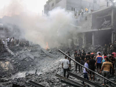 People extinguish a fire in the site of Israeli air strikes in Rafah on October 12, 2023.