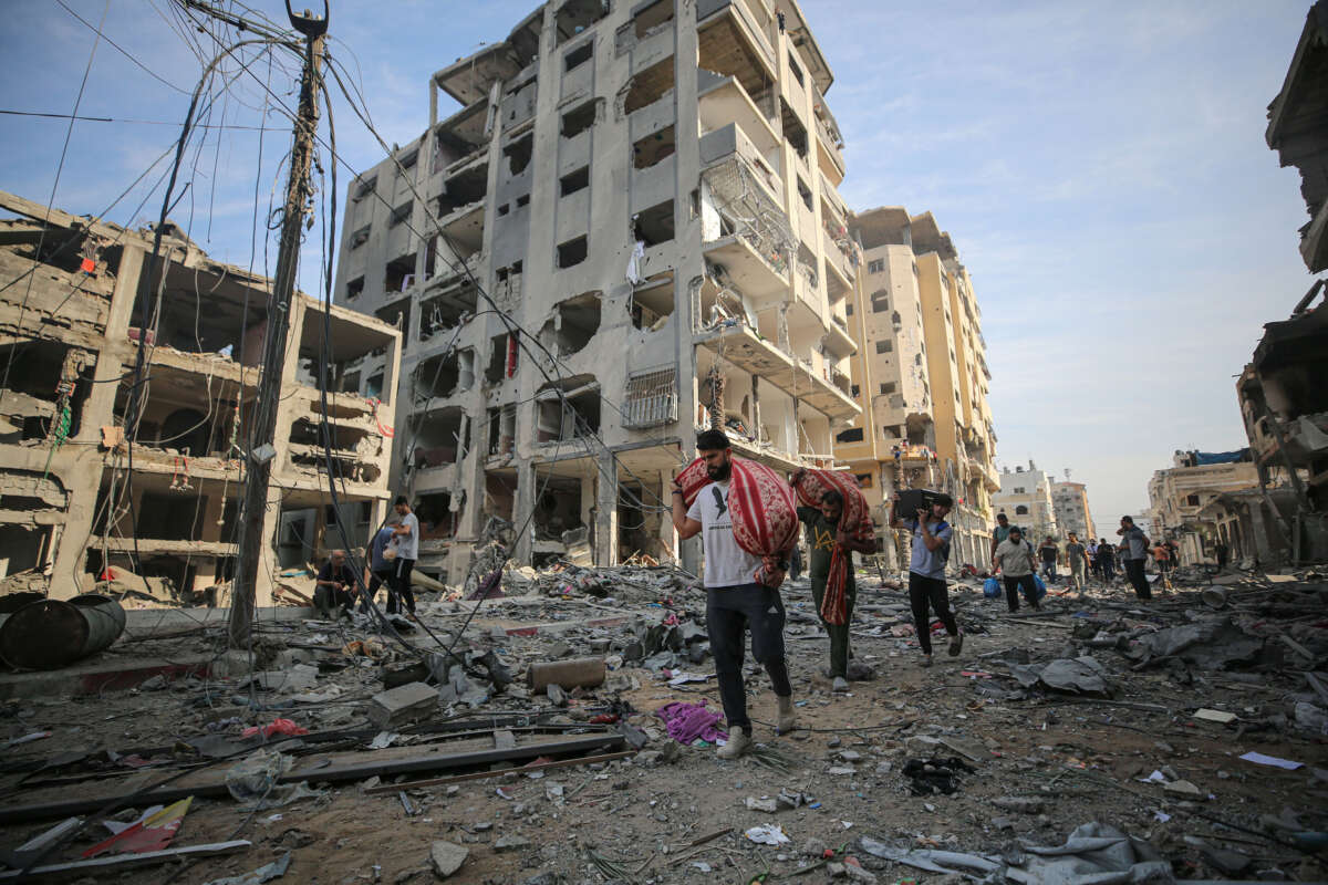 People carry their belongings around destroyed buildings and debris at the Al-Karama neighborhood after an Israeli airstrike that has been going on for five days in Gaza City on October 11, 2023.