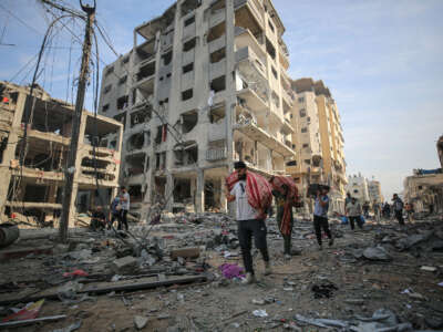 People carry their belongings around destroyed buildings and debris at the Al-Karama neighborhood after an Israeli airstrike that has been going on for five days in Gaza City on October 11, 2023.