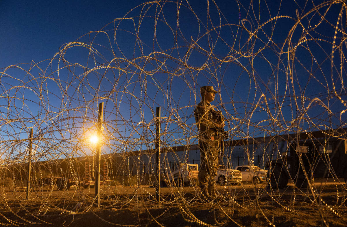 A Texas National Guard soldier stands vigil at a makeshift migrant camp near the U.S.-Mexico border fence on May 11, 2023, in El Paso, Texas.