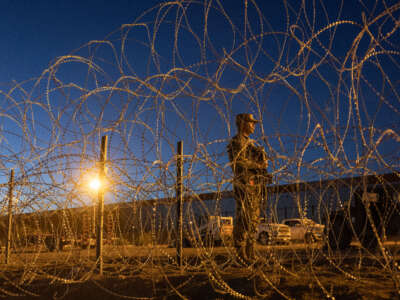 A Texas National Guard soldier stands vigil at a makeshift migrant camp near the U.S.-Mexico border fence on May 11, 2023, in El Paso, Texas.
