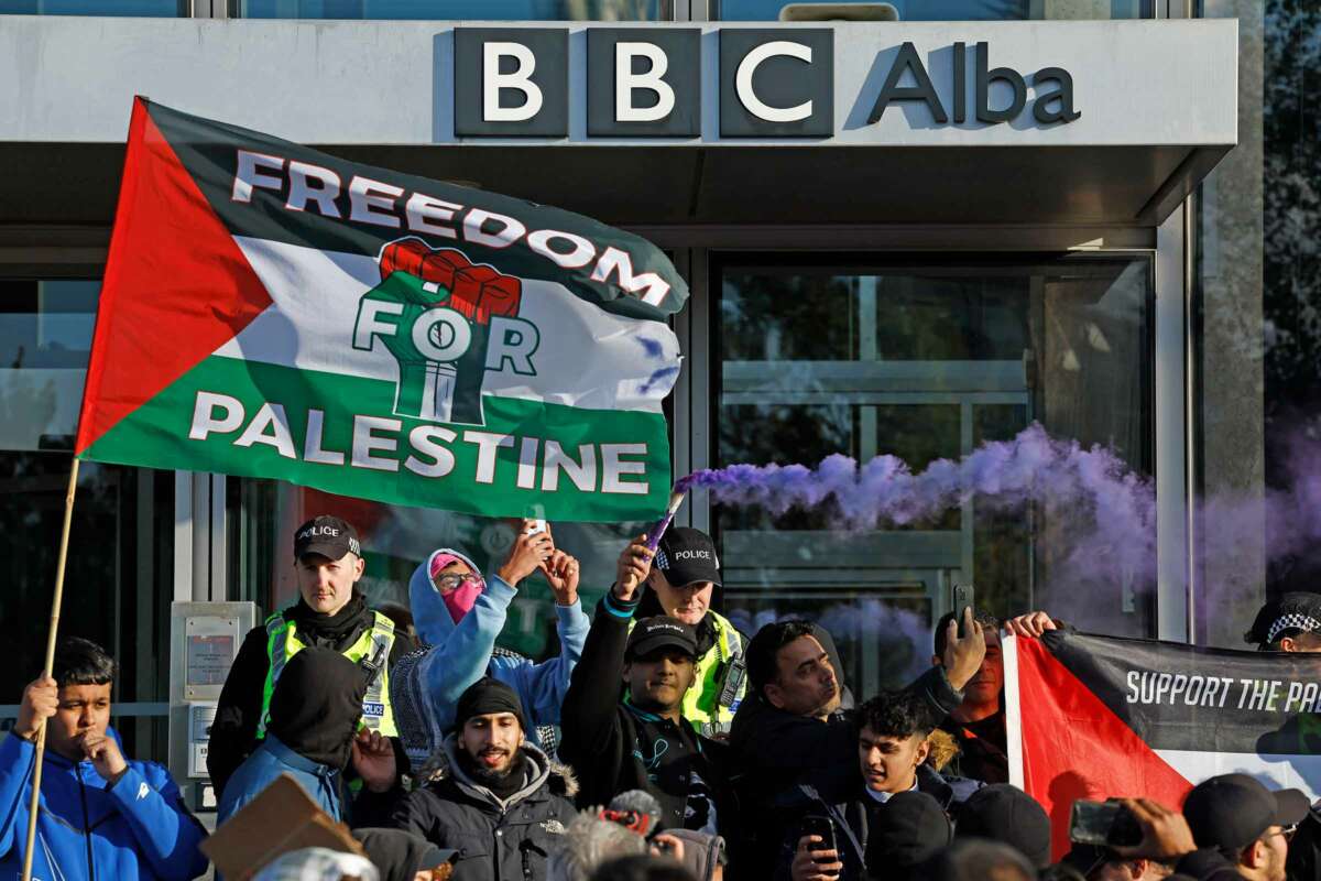 People wave Palestinian flags outside of the BBC headquarters during an outdoor demonstration