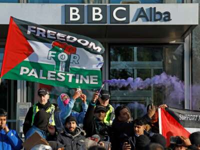 People wave Palestinian flags outside of the BBC headquarters during an outdoor demonstration