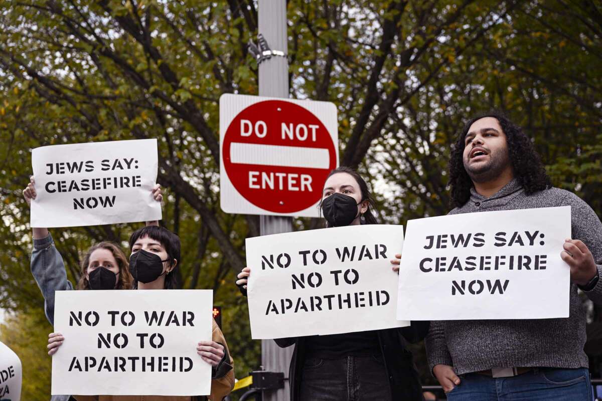 People hold signs reading "JEWS SAY: CEASEFIRE NOW" and "NO TO WAR; NO TO APARTHEID" during an outdoor protest