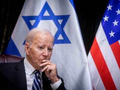 Joe Biden sits in front of the Israeli flag during a meeting