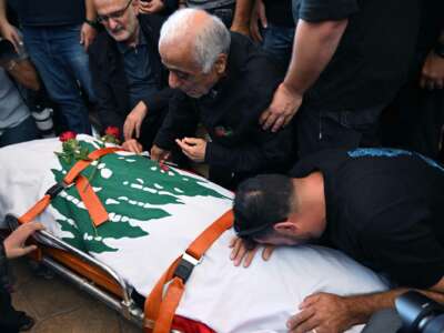 Mourners embrace the Lebanon flag-shrouded body of slain journalist Issam Abdallah