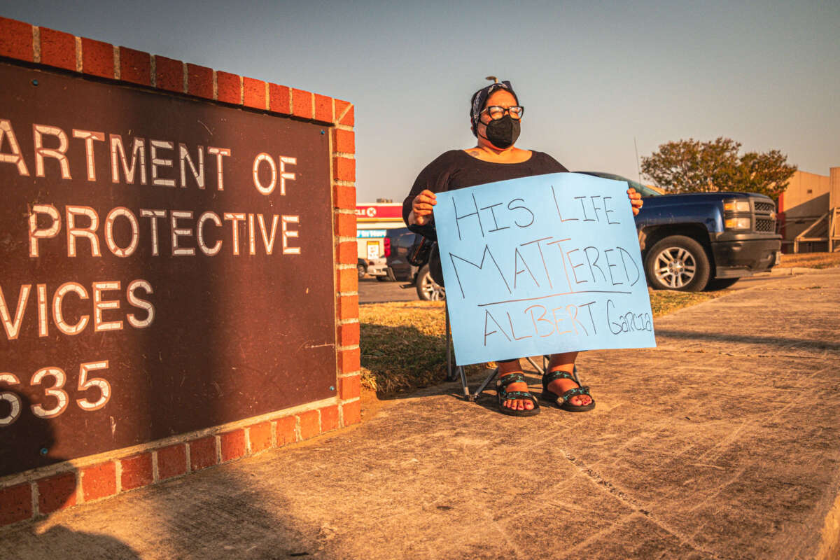 'Lotus' of the Harlandale Pantry protesting outside state Family & Protective Services office.