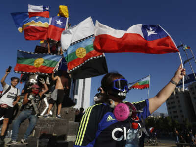 Demonstrators wave Chilean and Indigenous flags during a protest in Chile