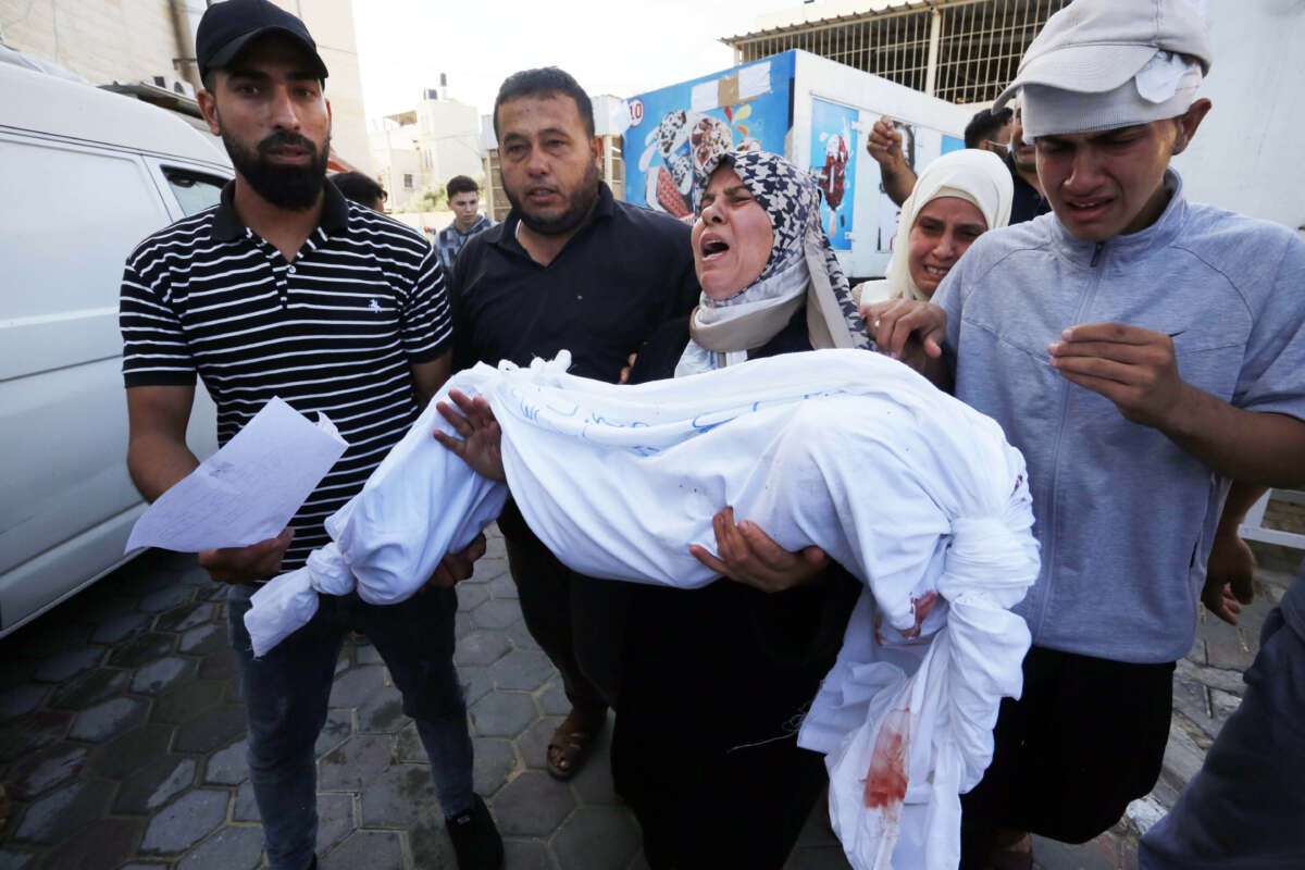 A woman carries a dead body of a child to the morgue of the Suheda al-Aqsa Hospital as Israel's attacks on the Gaza Strip continue in Deir al-Balah, Gaza, on October 14, 2023.