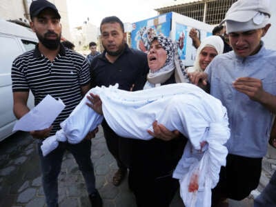 A woman carries a dead body of a child to the morgue of the Suheda al-Aqsa Hospital as Israel's attacks on the Gaza Strip continue in Deir al-Balah, Gaza, on October 14, 2023.