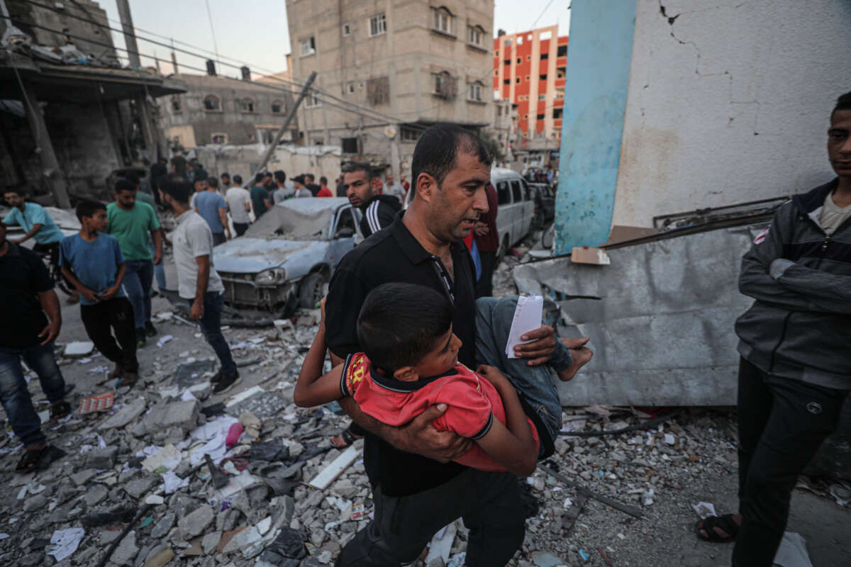 A man carries a rescued child amid rubble from an airstrike in Gaza