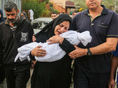 A woman mourns as she holds the body of a child killed in Israeli air raids on October 28, 2023, in Khan Yunis, Gaza.