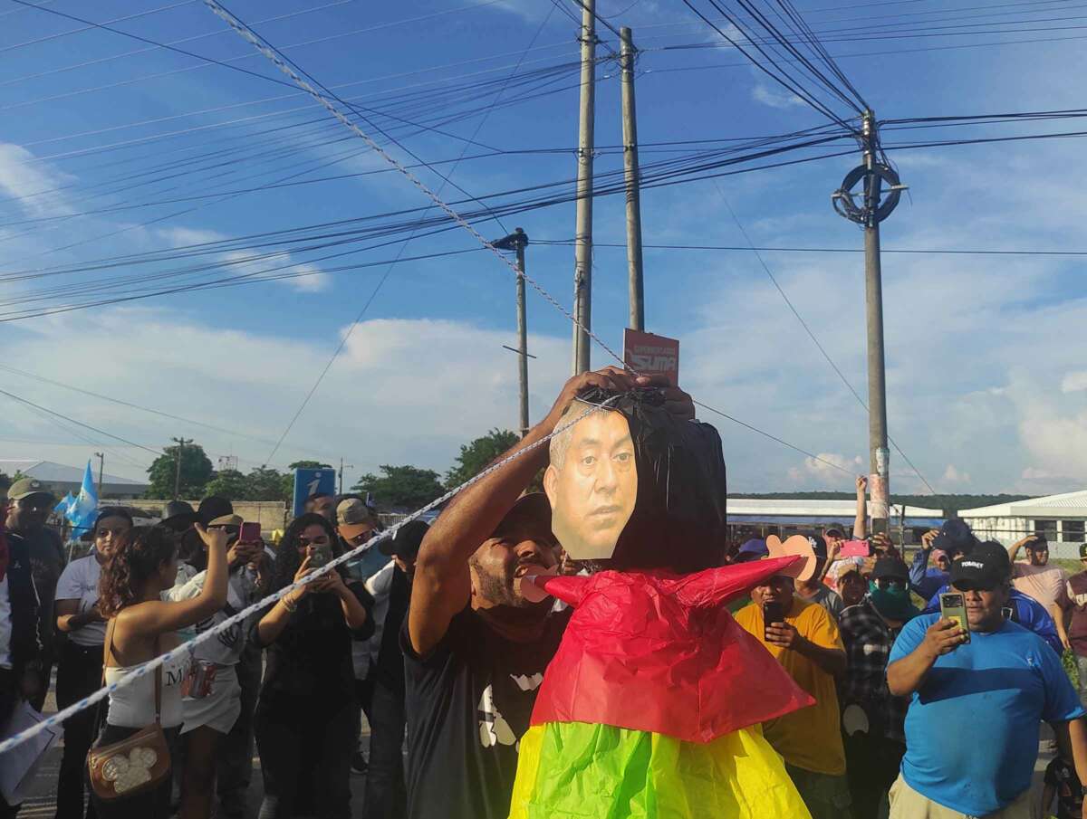 At a blockade in Santa Elena, Petén, a protester strings up a piñata featuring the face of special anti-impunity prosecutor Rafael Curruchiche.