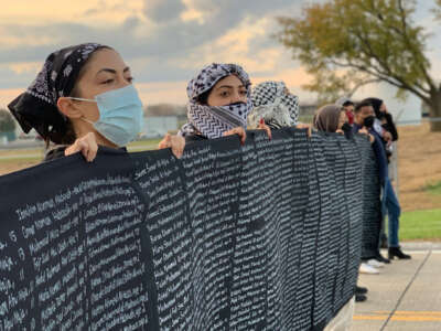 Members of the Palestinian solidarity coalition stand in front of Boeing holding up a banner with the names of 1,300 of the more than 4,100 Palestinian children who have been killed by the Israeli military in Gaza.