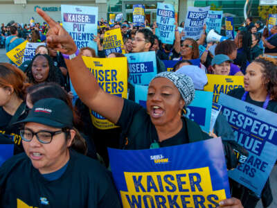 A woman points forward as Kaiser employees picket in Los Angeles, California