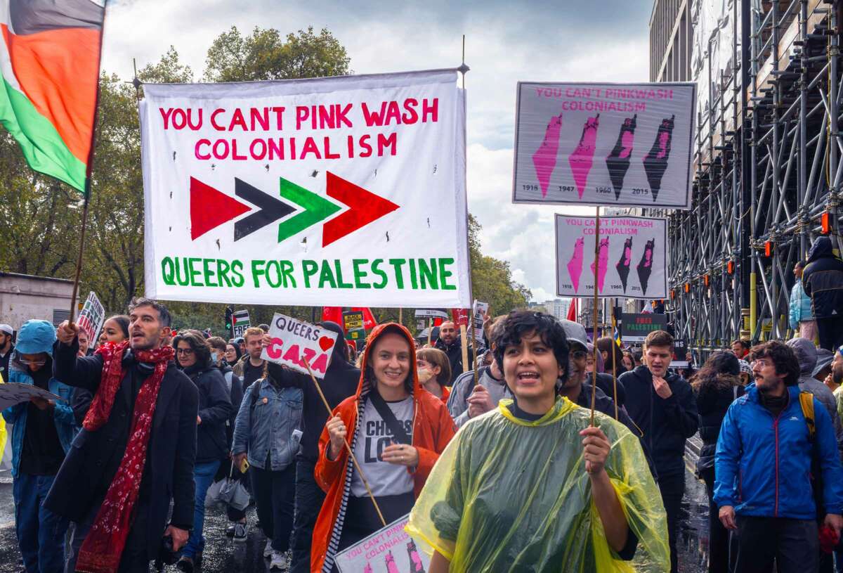 Protesters march under a banner reading "YOU CAN'T PINKWASH COLONIALISM; QUEERS FOR PALESTINE" during an outdoor demonstration