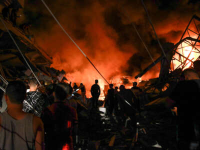 Smoke and fire rise from buildings as people gather amid the destruction in the aftermath of an Israeli strike on Gaza City on October 26, 2023.