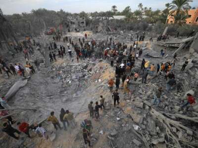 People gather among the rubble of what was once their neighborhood