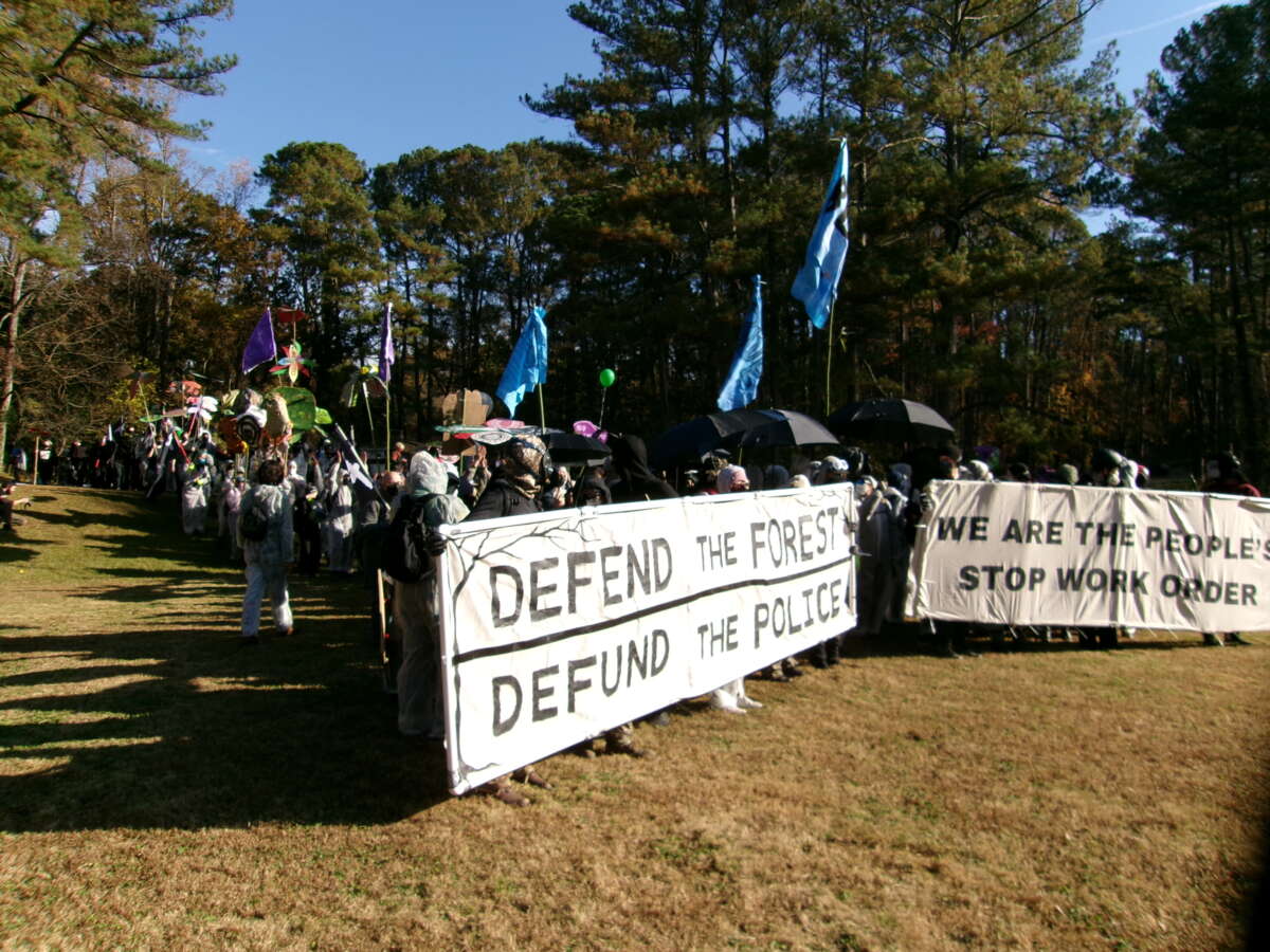 Manifestantes con pancartas marchan hacia el sitio de construcción de Cop City el 13 de noviembre de 2023.