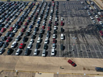 An aerial view shows cars lined up in a parking lot as people wait to be directed to a food distribution point setup at Del Valle High School on February 20, 2021, in Austin, Texas.