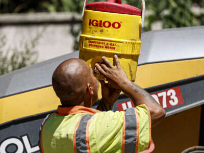 LA County crew member Jonathan Lainez hydrates as he works to repave a section of East Altadena Dr. as temperatures reach 100 degrees and above in Altadena, California, on August 28, 2023.