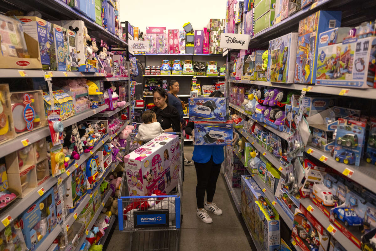 Walmart employee stocks toy department shelves as shoppers peruse merchandise