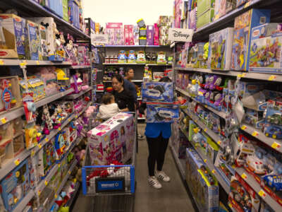Walmart employee stocks toy department shelves as shoppers peruse merchandise