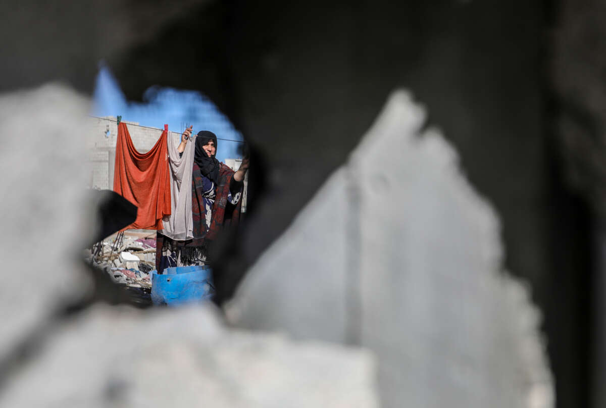 A woman washes and dries clothes amongst the destruction caused by airstrikes on homes in Khan Yunis, Gaza, on November 29, 2023.