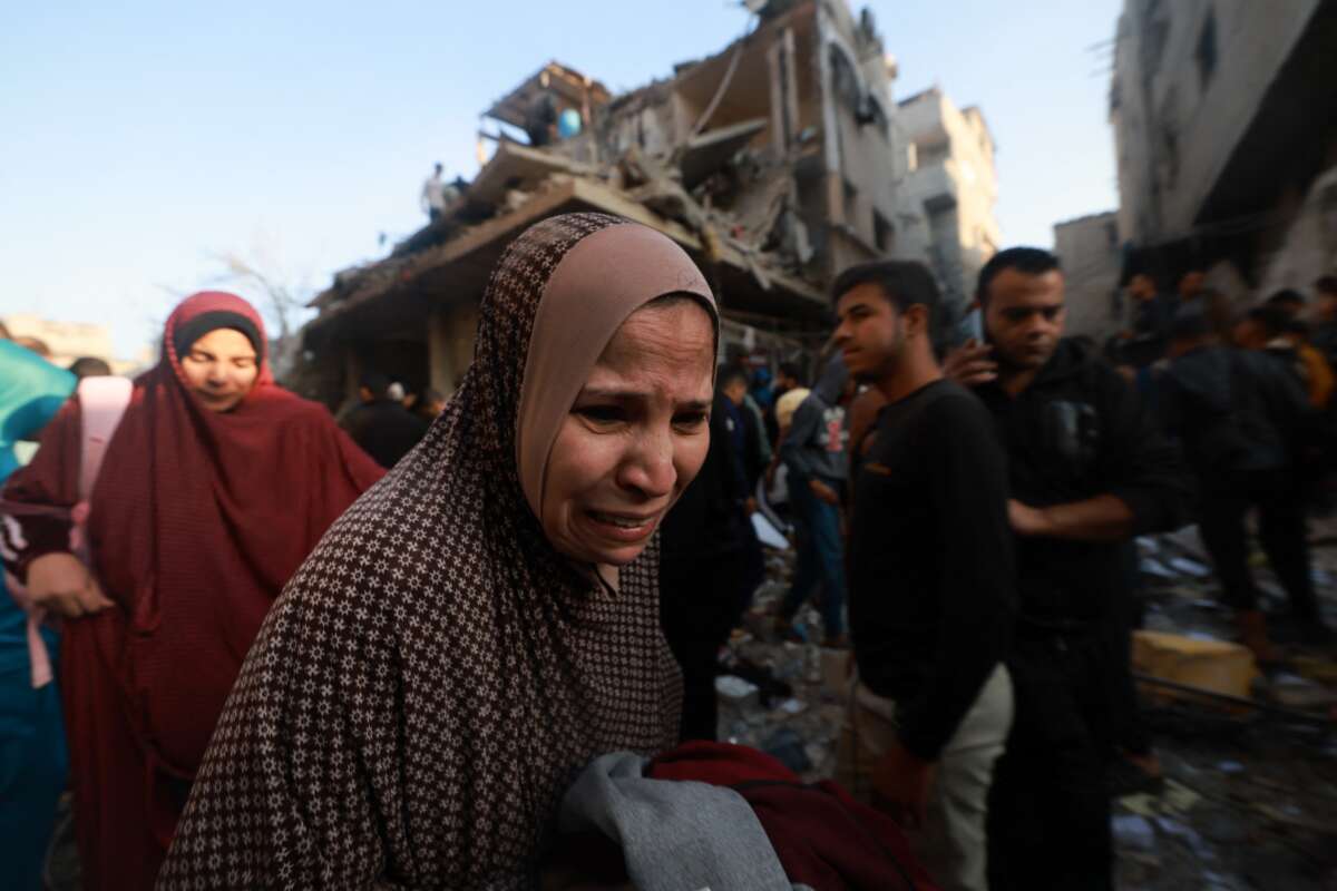 A Palestinian woman reacts as people check the rubble of a building destroyed in Israeli air strikes on the Rafah refugee camp in the southern Gaza Strip on December 1, 2023.
