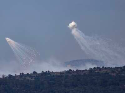 A picture taken from the Israeli side of border with Lebanon shows shells exploding over hills around the southern Lebanese village of Aita al-Shaab on December 8, 2023.