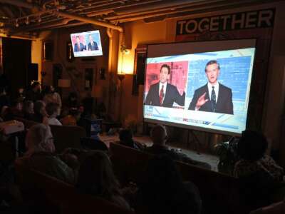 People in a darkened bar watch a televised broadcast of the Gavin Newsom and Ron DeSantis debate
