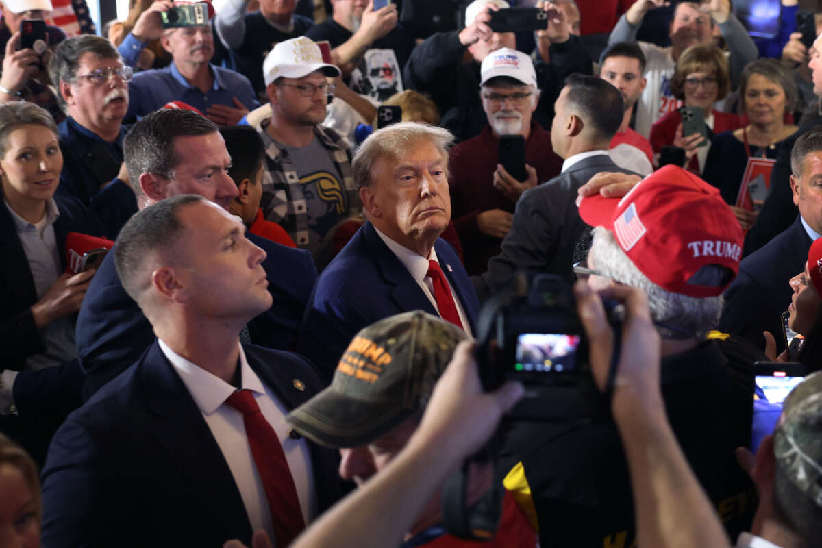 Former President Donald Trump greets guests as he arrives at a commit to caucus campaign event at the Whiskey River bar on December 2, 2023, in Ankeny, Iowa.