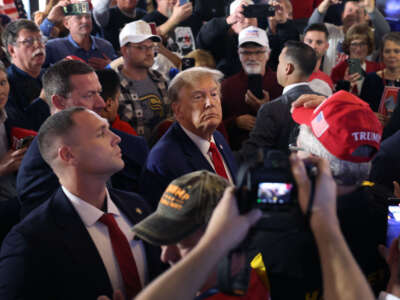 Former President Donald Trump greets guests as he arrives at a commit to caucus campaign event at the Whiskey River bar on December 2, 2023, in Ankeny, Iowa.