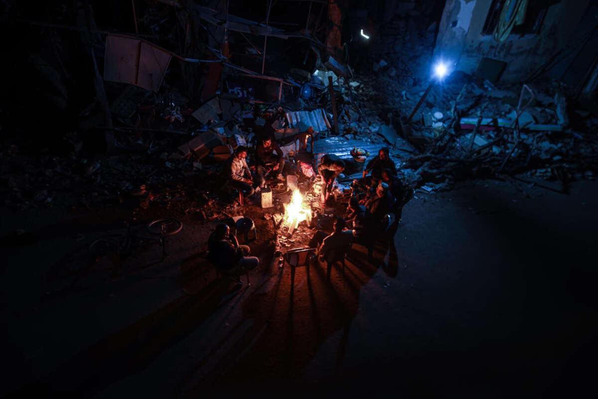 Palestinian citizens sit in front of their destroyed homes and light fires on the third day of the humanitarian truce, east of the city of Khan Yunis, Palestine, on December 1, 2023.