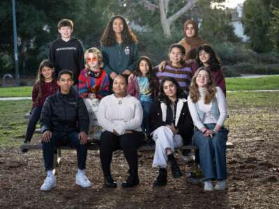 A group of kids gather on a park bench for an outdoor photo