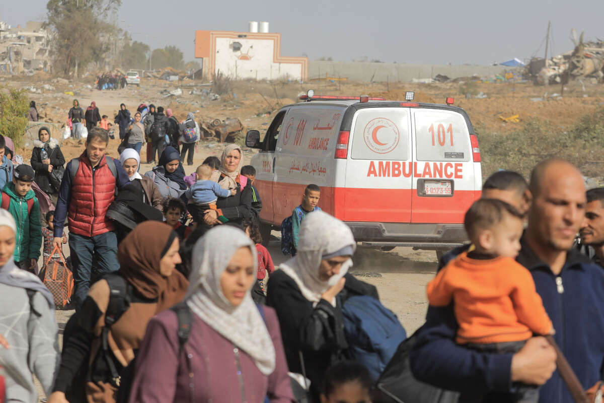 Palestinians pass by an ambulance vehicle in the Al-Zaytoun area on the third day of the truce between Israel and Hamas on November 26, 2023.