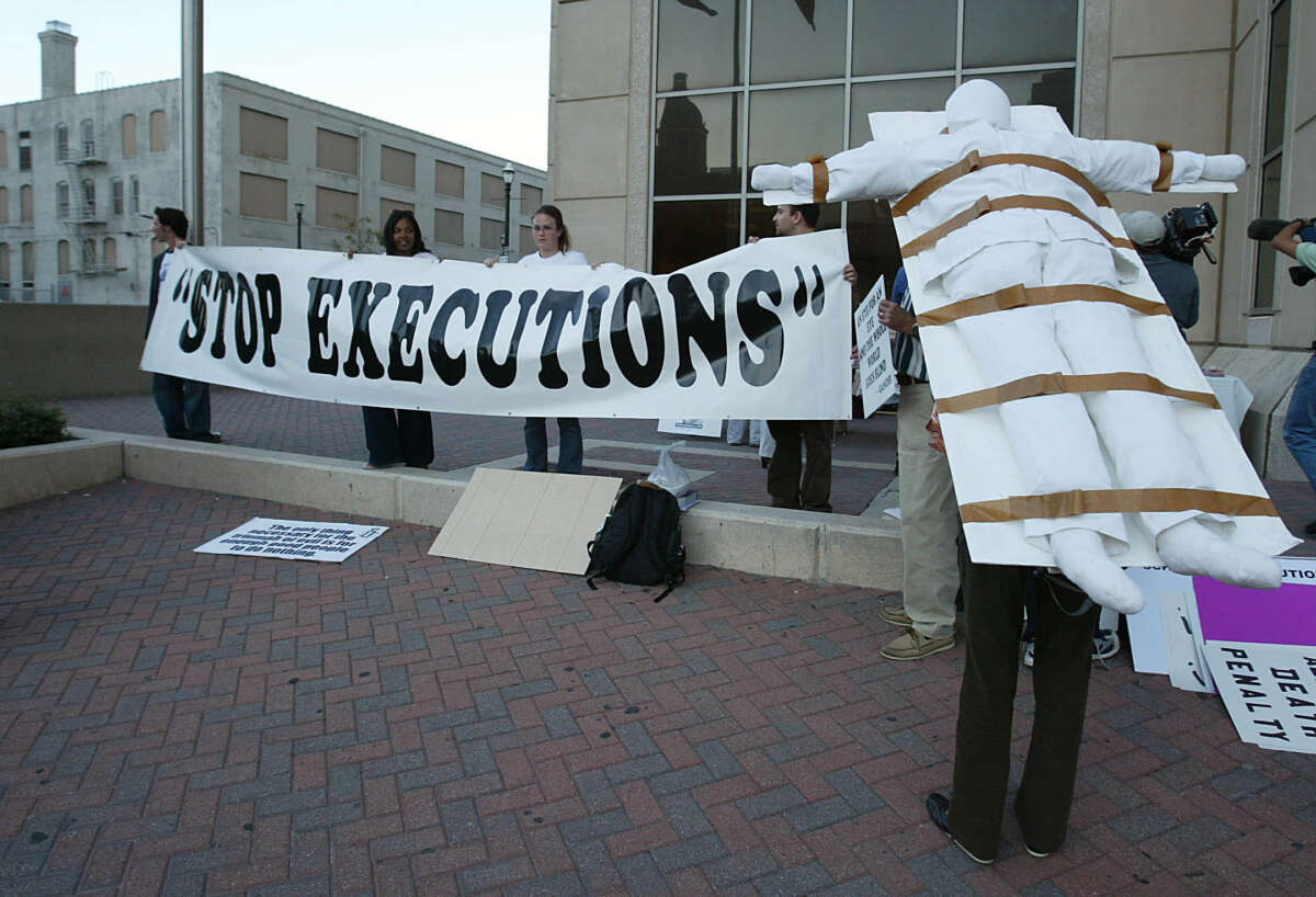 A protester stands with a model of a gurney strapped to her back at Amnesty International's Stop Death Penalty in Texas Now demonstration outside the Harris County Criminal Justice Center in Houston, Texas, on November 5, 2004.