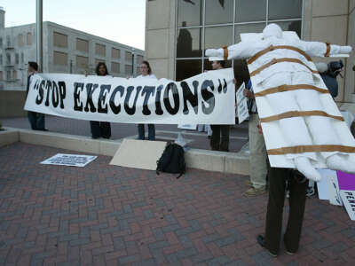 A protester stands with a model of a gurney strapped to her back at Amnesty International's Stop Death Penalty in Texas Now demonstration outside the Harris County Criminal Justice Center in Houston, Texas, on November 5, 2004.