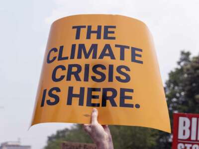 A yellow sign reading "The Climate Crisis Is Here" at the Stop Mount Valley Pipeline rally held in front of the White House in Washington, D.C. on June 8, 2023.