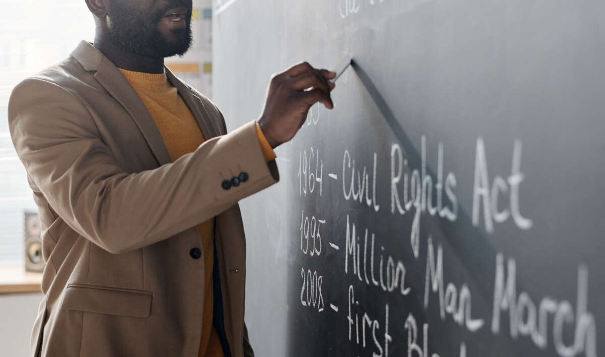 Black teacher writes on chalkboard
