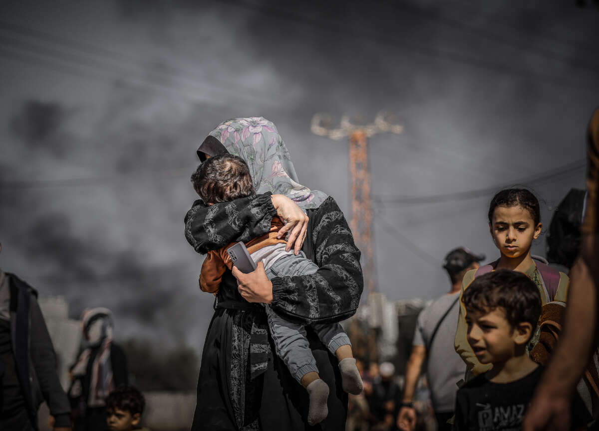 A mother in northern Gaza covers her child's face for protection against smoke as Palestinians flee from Israel's bombing of the Gaza Strip on November 10, 2023.