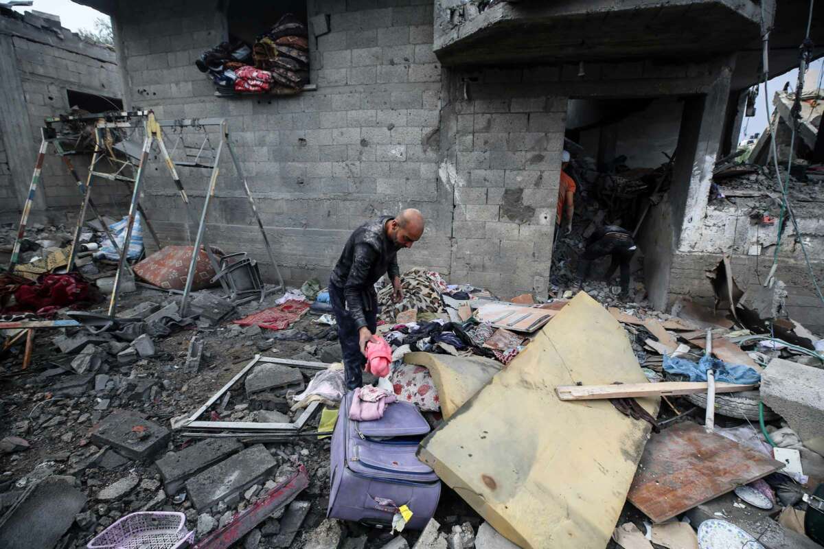 A man sifts through discarded luggage as he walks through a destroyed refugee camp